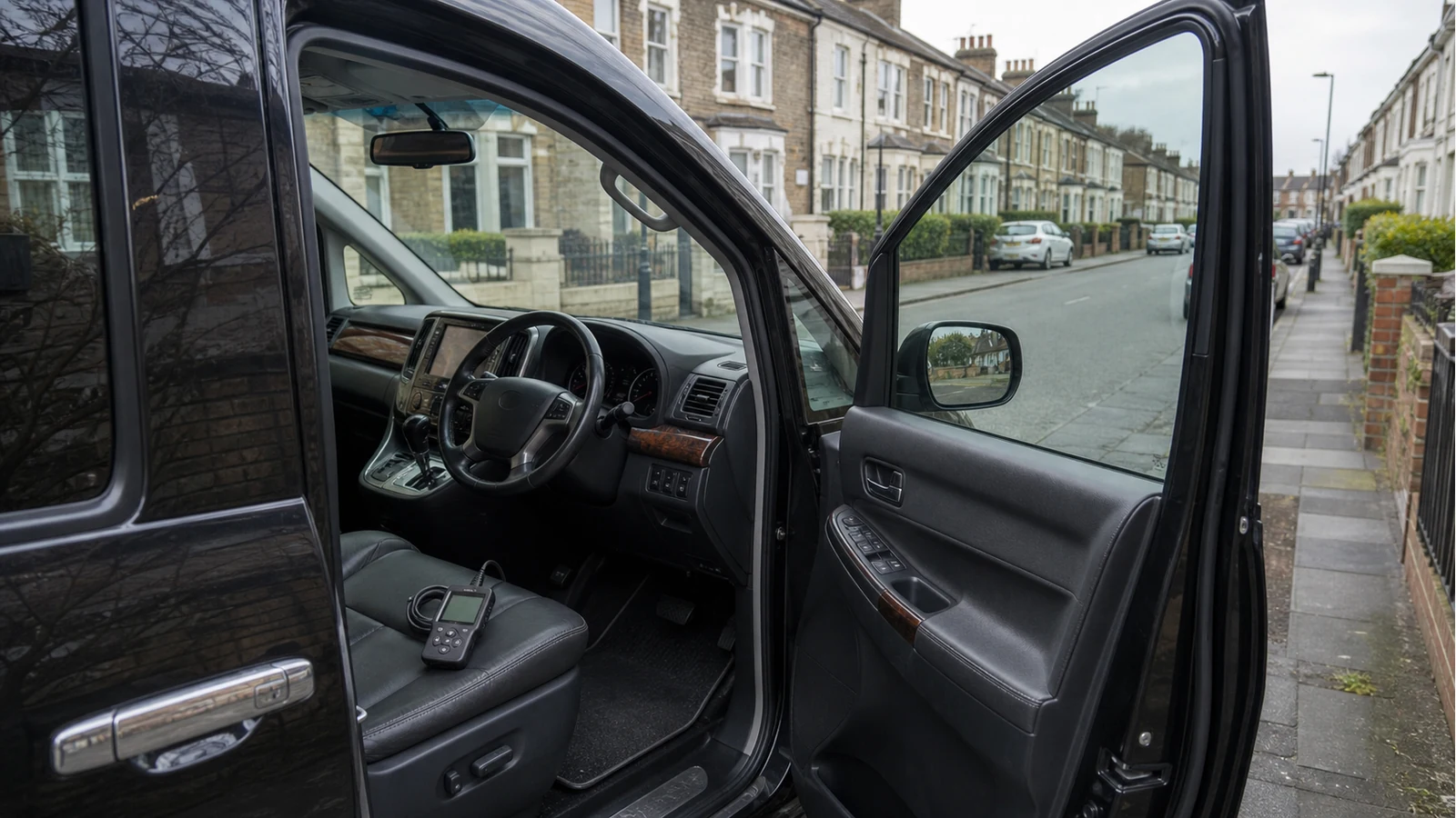 Compact handheld engine code reader on the seat of a UK-registered Japanese MPV import
